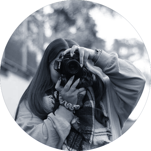 Portrait d'une jeune femme, elle tient un appareil photo réflex en face de son visage